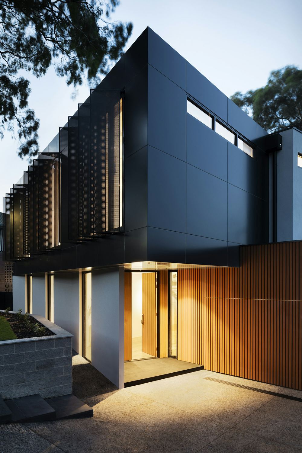 Dark timber facade with warm lit entrance at dusk