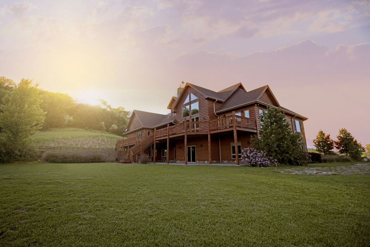 Timber house on a green hillside at sunset